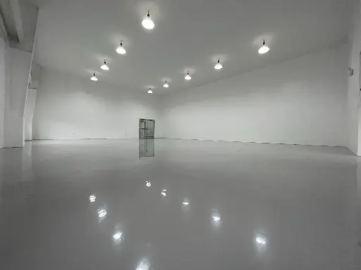 This image depicts a large white room of a manufacturing plant with newly installed grey epoxy flooring by Carmacoat
