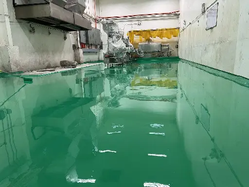 The image depicts a processing plant's production floor with a newly installed signal green epoxy flooring by Carmacoat