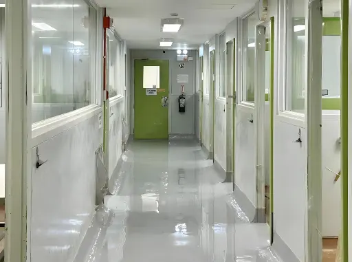 The image depicts a laboratory hallway with freshly installed grey epoxy flooring done by Carmacoat