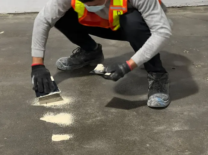 The image depicts a carmacoat employee filling small cracks and crevices using epoxy putty and a scraper